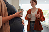 Pregnant woman and friend talking and drinking tea