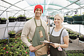 Happy plant nursery owners working in greenhouse