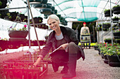 Happy garden shop owner working in greenhouse