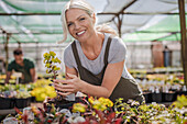 Happy female garden shop owner with plants