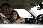 Happy couple drinking coffee inside car