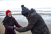 Happy playful couple dancing on winter beach