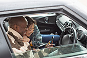 Happy couple using smart phone in car window