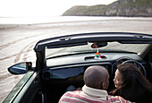 Affectionate couple hugging in convertible on beach