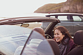 Happy couple in convertible at beach