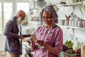 Woman using smart phone in kitchen