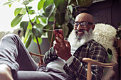 Happy man using smart phone in armchair