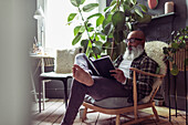 Barefoot man with beard reading book at home