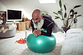 Man with beard exercising with fitness ball at home