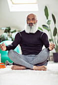 Mature man with beard meditating in lotus position