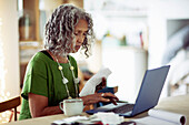Woman with receipts banking at laptop
