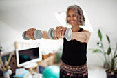 Woman exercising with dumbbells at home