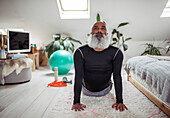 Man with beard practicing yoga upward facing dog at home