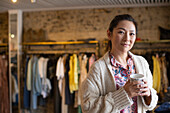 Confident female shop owner with tea in boutique