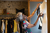 Senior female shop owner arranging display in boutique