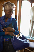 Smiling woman trying on blue handbag in boutique