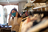 Woman adjusting face mask in clothing boutique