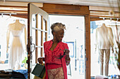 Smiling senior woman entering clothing boutique