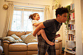 Brother piggybacking happy sister in living room