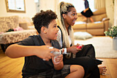 Mother and son playing video game on living room floor