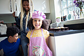 Happy girl in unicorn apron in kitchen with family