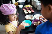 Brother and sister baking cupcakes with sprinkles