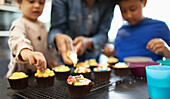 Mother and kids decorating cupcakes