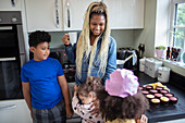 Happy mother and kids baking cupcakes in kitchen