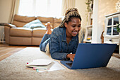 Happy woman working from home at laptop on living room floor