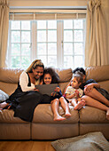 Mother and kids using digital tablet on living room sofa