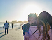 Boy with Down Syndrome over shoulder of mother on beach