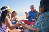 Family playing clapping game on sunny beach