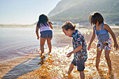 Boy with Down Syndrome and sisters wading in sunny ocean