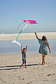 Mother and son playing with kite on beach