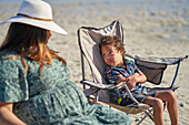 Boy with Down Syndrome in beach chair looking at mother