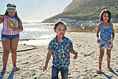 Sisters and brother playing with bubbles on beach