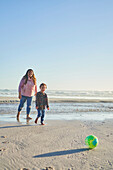 Mother and son playing with soccer ball on beach