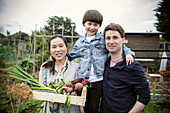 Happy family with harvested vegetables on allotment