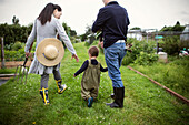 Parents and toddler son walking on allotment
