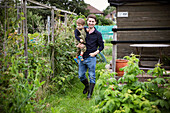 Happy father carrying toddler son on allotment