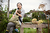 Happy mother holding tired toddler son on garden bench