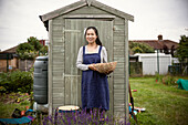 Smiling woman with basket next to shed