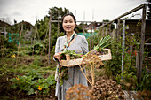 Woman with crate of harvested vegetables in garden
