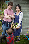 Family with harvested vegetables in garden