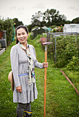 Smiling woman with rake in garden