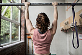 Muscular young woman working out at bar in gym