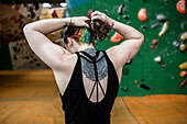 Young woman with back tattoo at climbing wall