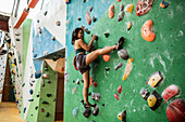 Woman with headphones on climbing wall