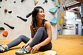 Smiling woman sitting below rock climbing wall