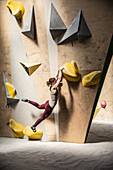 Young woman hanging from climbing wall